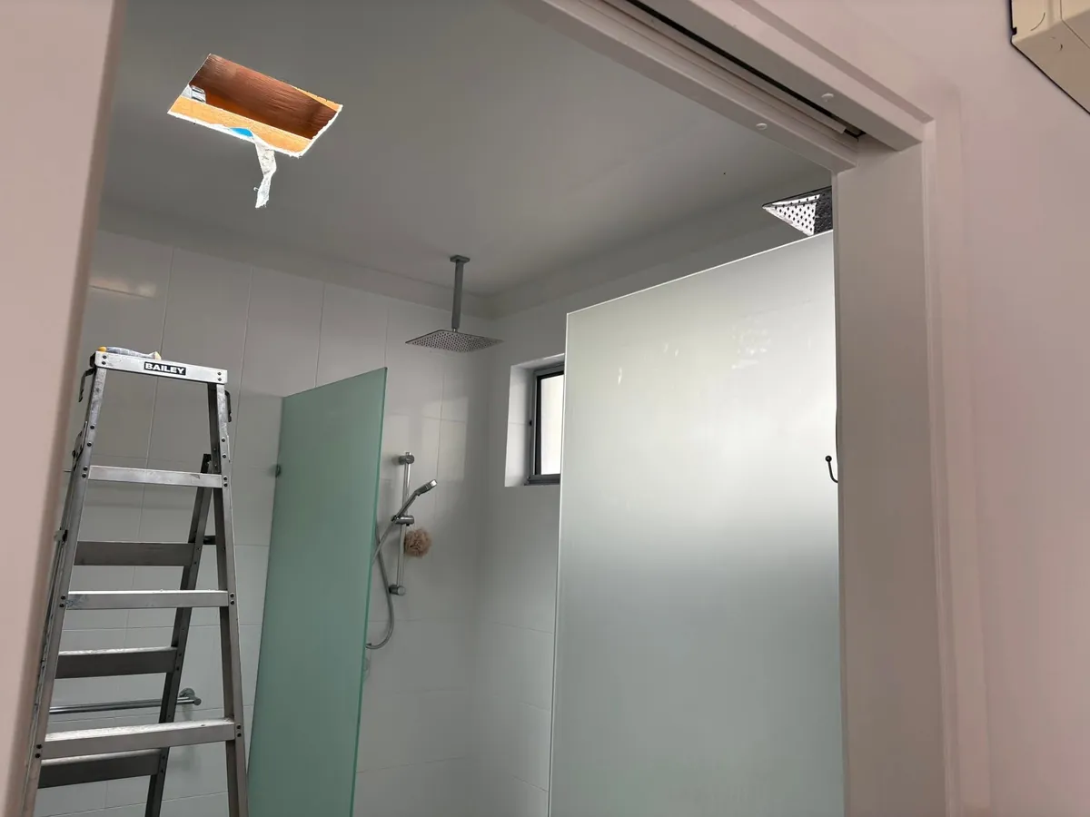 Shower ceiling with the skylight opening freshly cut and a ladder
