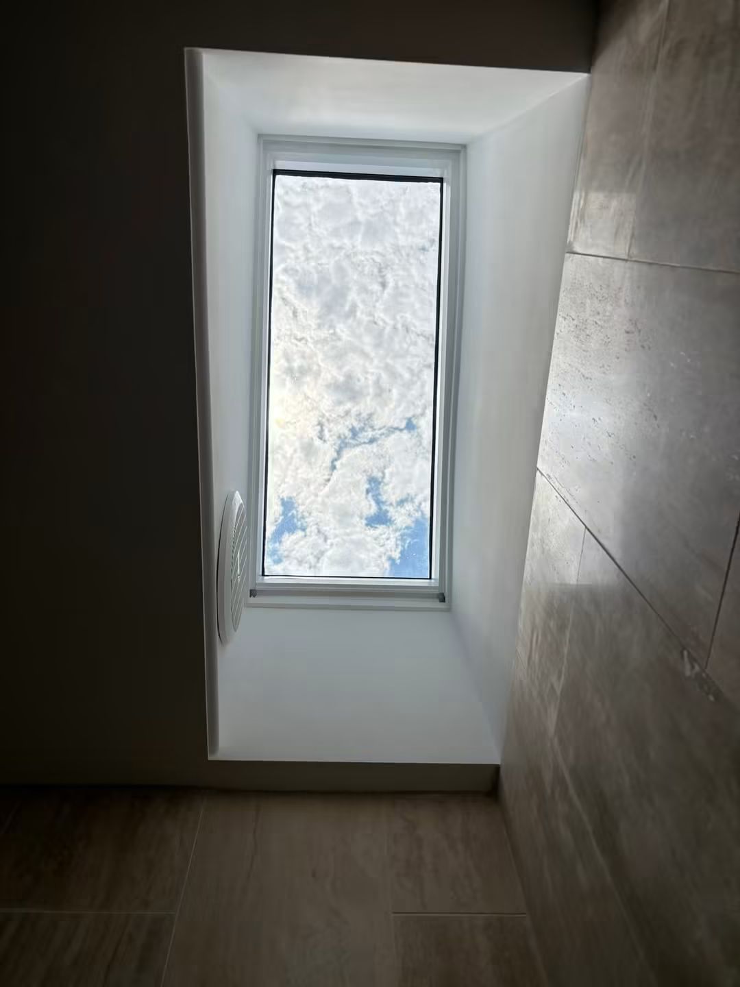 Tall skylight shaft in a stone-tiled bathroom
