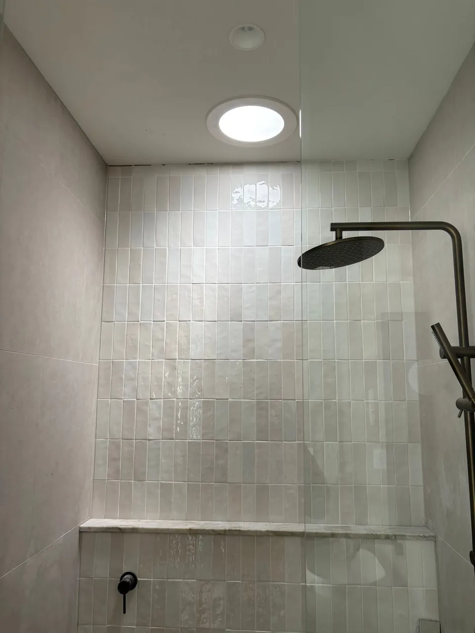 Round ceiling fitting above a tiled shower