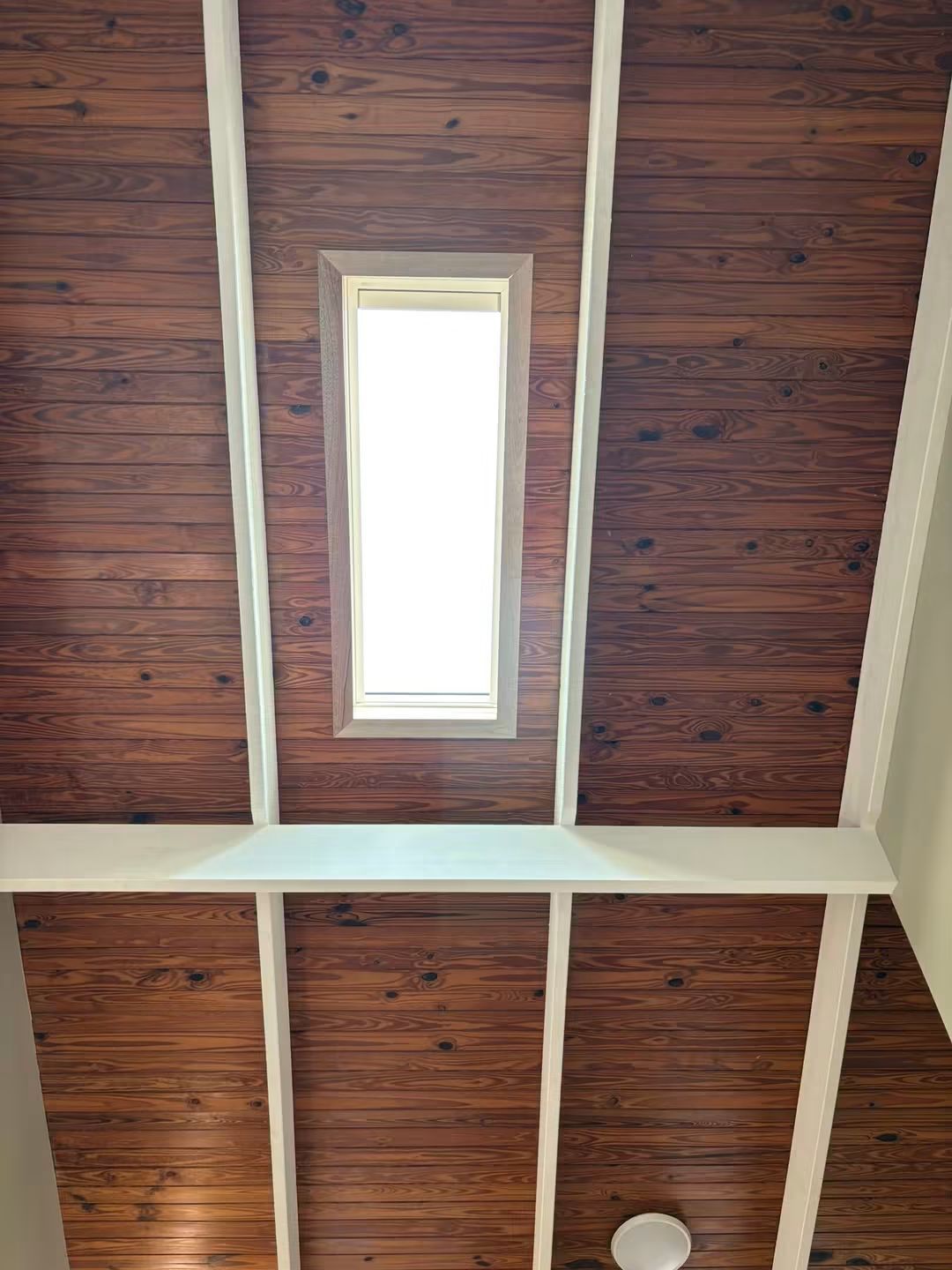Narrow skylight in a timber-lined hallway