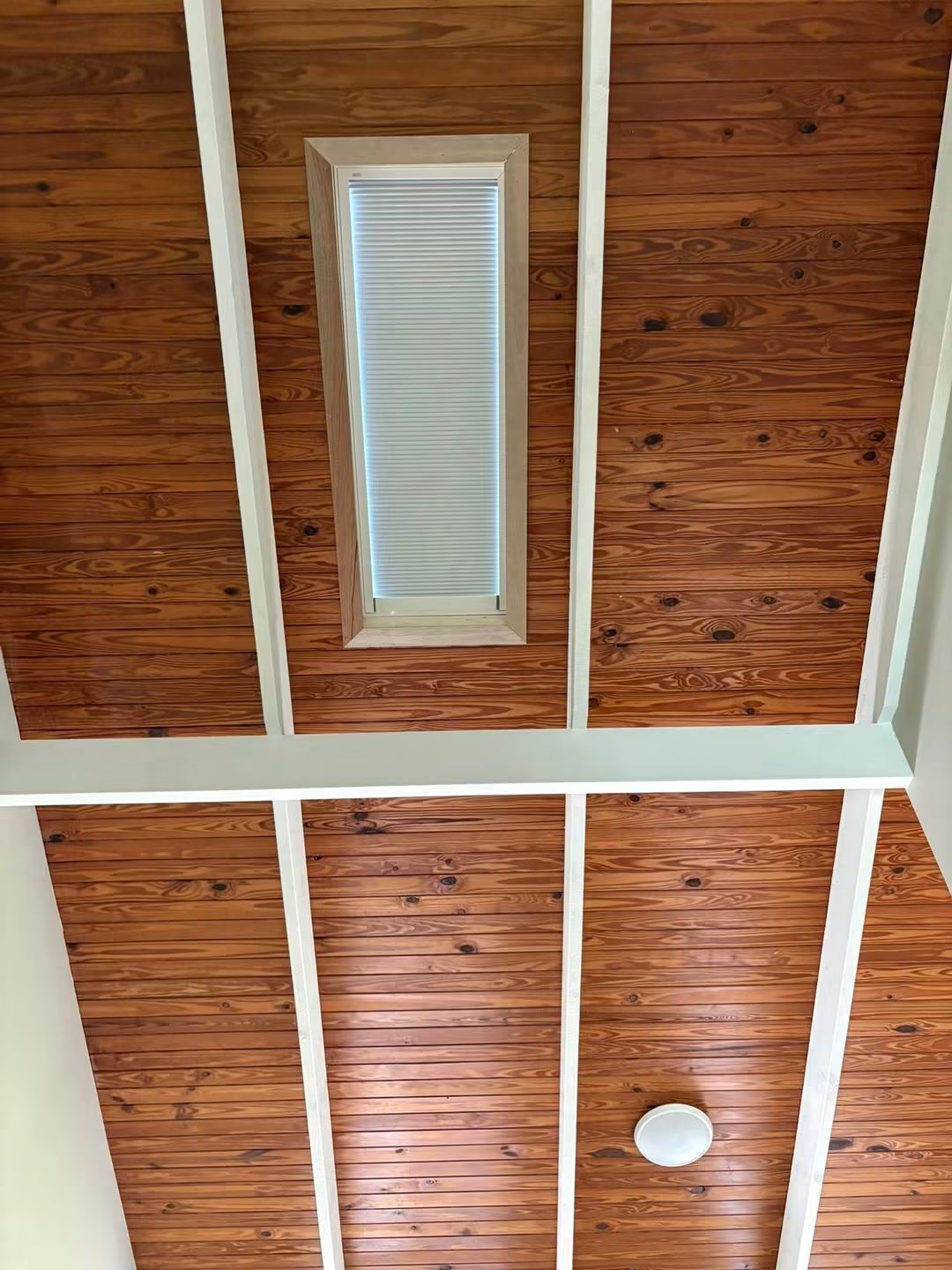 Slim skylight between ceiling beams in a hallway