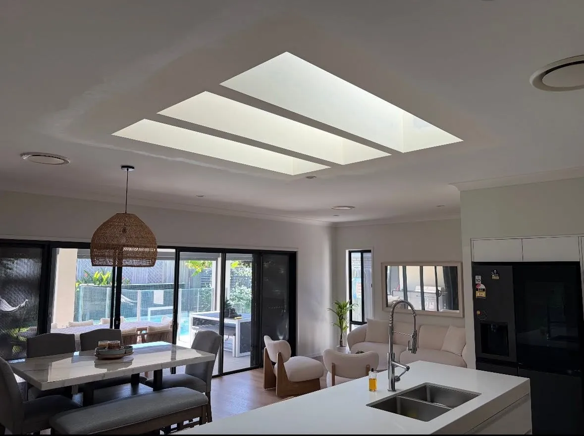 Three skylights in a row above a modern kitchen and dining area