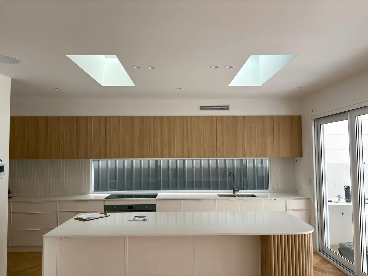 Two skylights above a kitchen island with timber cabinets