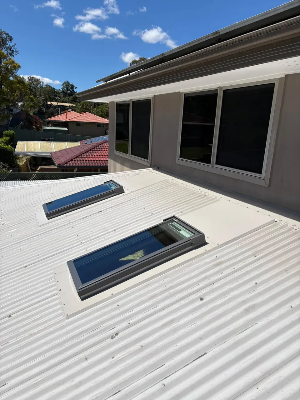 Two roof windows on a metal roof below a second storey